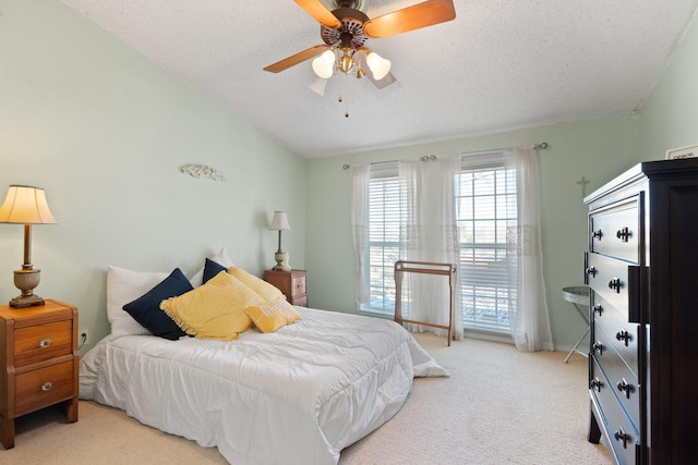 bedroom with a textured ceiling, light colored carpet, and ceiling fan