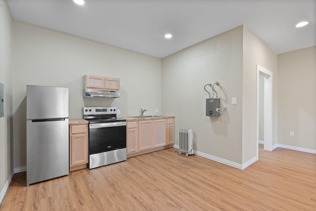 kitchen featuring radiator heating unit, stainless steel appliances, light brown cabinets, and sink