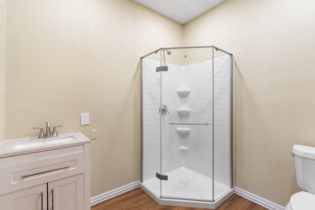 bathroom with toilet, vanity, walk in shower, and wood-type flooring