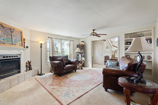 carpeted living room featuring a tile fireplace and ceiling fan