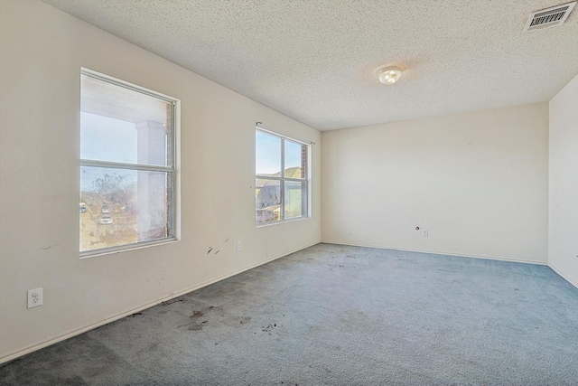 carpeted empty room with a textured ceiling