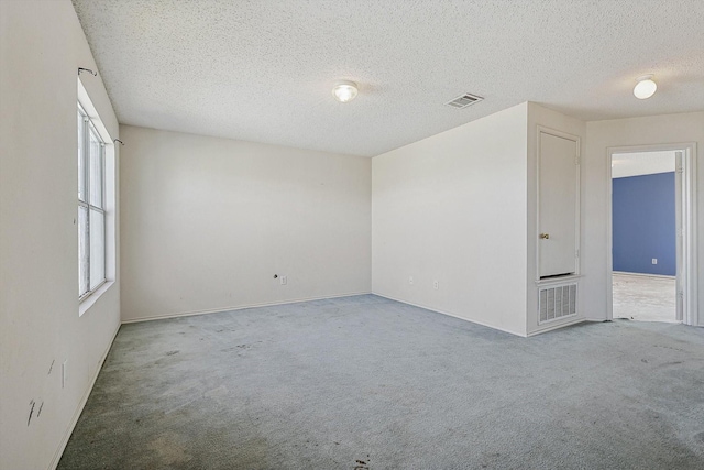 carpeted empty room with a textured ceiling