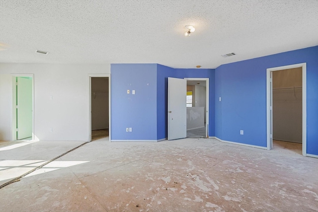 unfurnished bedroom featuring a spacious closet, a closet, and a textured ceiling