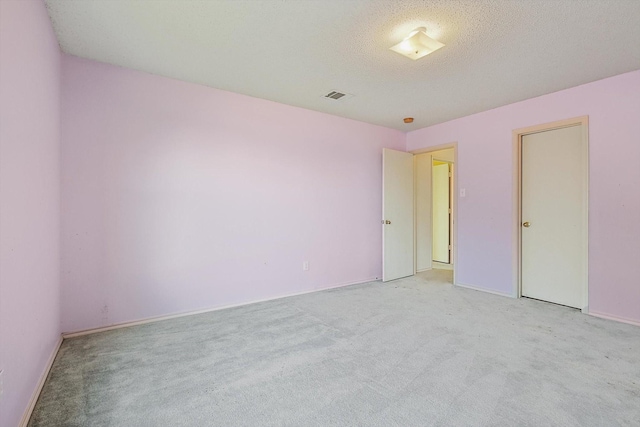 unfurnished room featuring light carpet and a textured ceiling