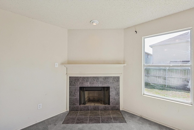 interior details featuring a tiled fireplace, a textured ceiling, and carpet