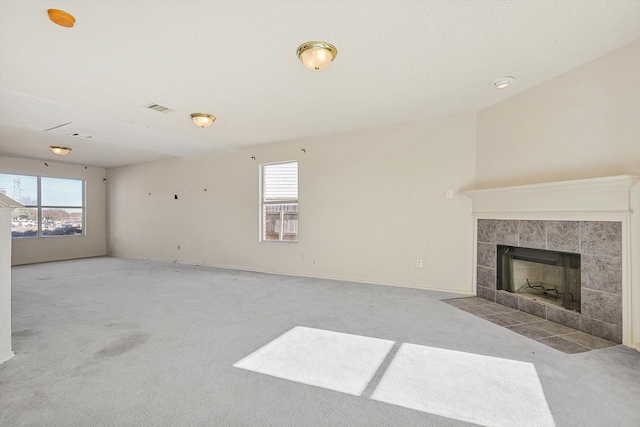 carpeted living room featuring a tiled fireplace and a wealth of natural light