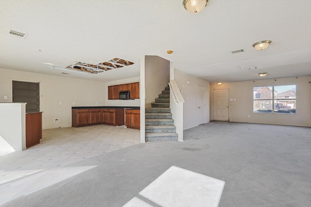 unfurnished living room featuring light carpet and a textured ceiling