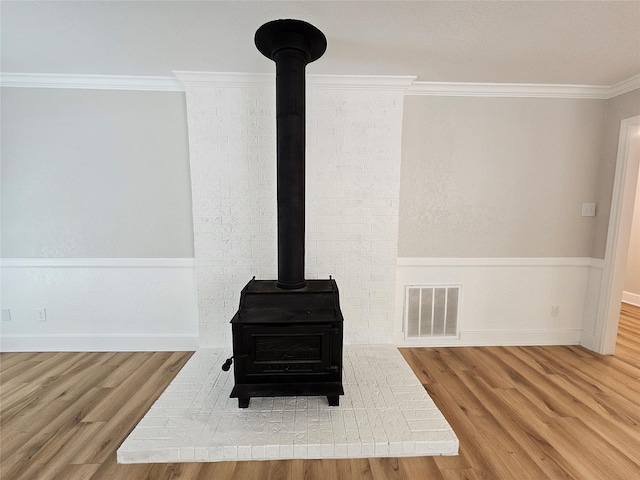 room details with crown molding, wood-type flooring, and a wood stove