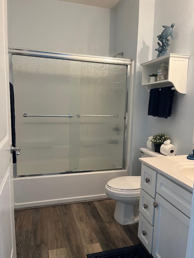 full bathroom featuring vanity, wood-type flooring, toilet, and combined bath / shower with glass door