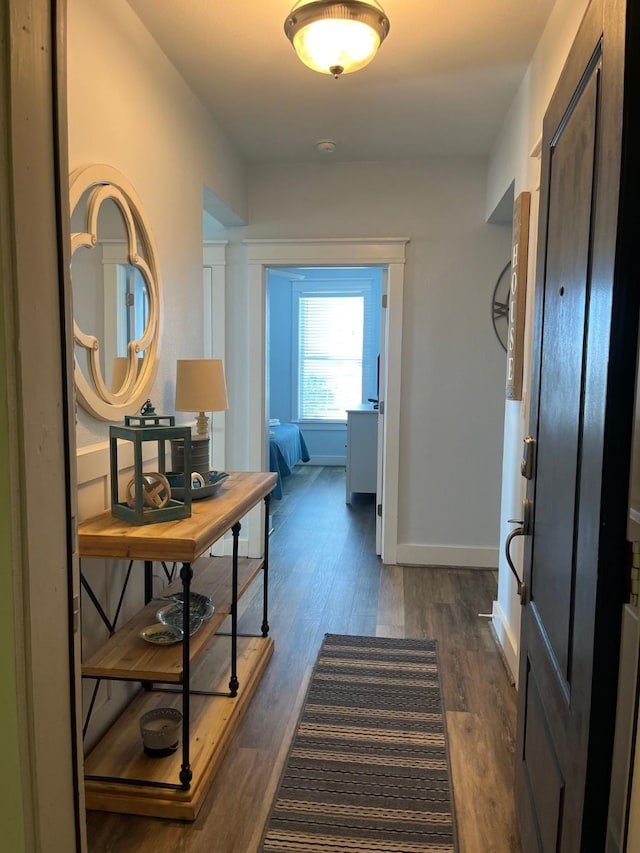 corridor with dark wood-type flooring and baseboards