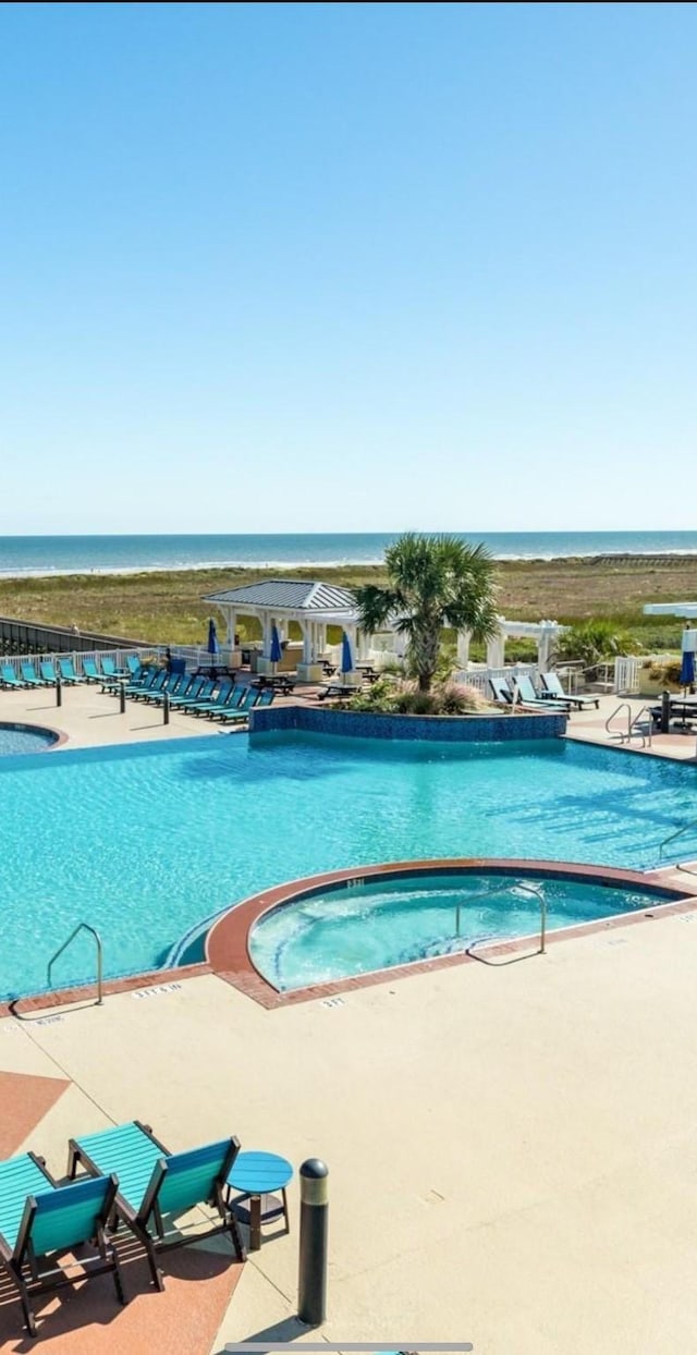 view of pool with a community hot tub, a water view, and a patio area