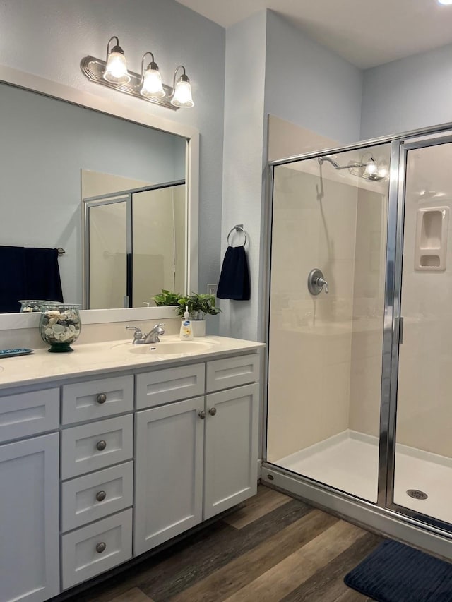 bathroom featuring wood-type flooring, an enclosed shower, and vanity