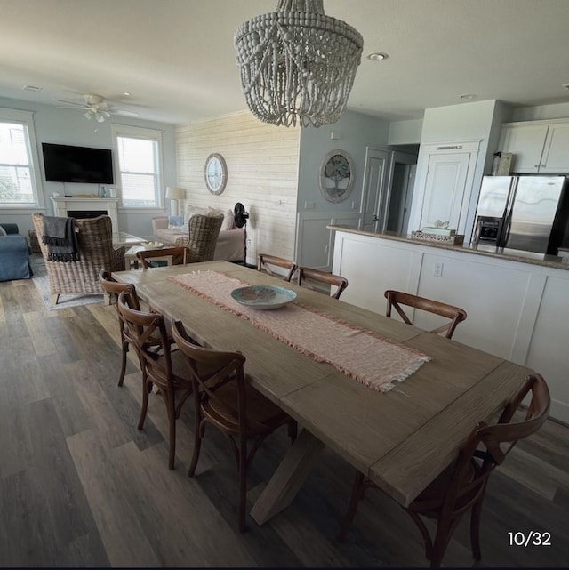 dining room with dark wood-type flooring, ceiling fan, and wood walls