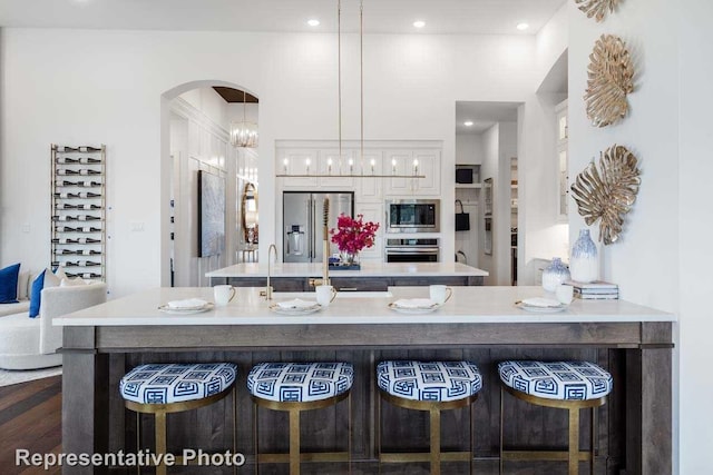 kitchen with dark hardwood / wood-style floors, white cabinetry, a kitchen bar, hanging light fixtures, and stainless steel appliances