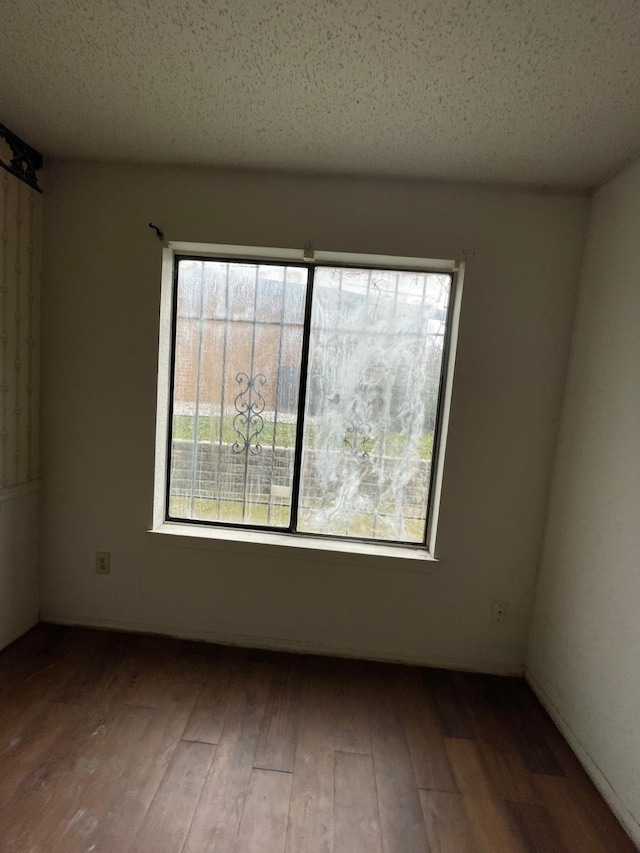 spare room featuring hardwood / wood-style flooring, a textured ceiling, and a healthy amount of sunlight