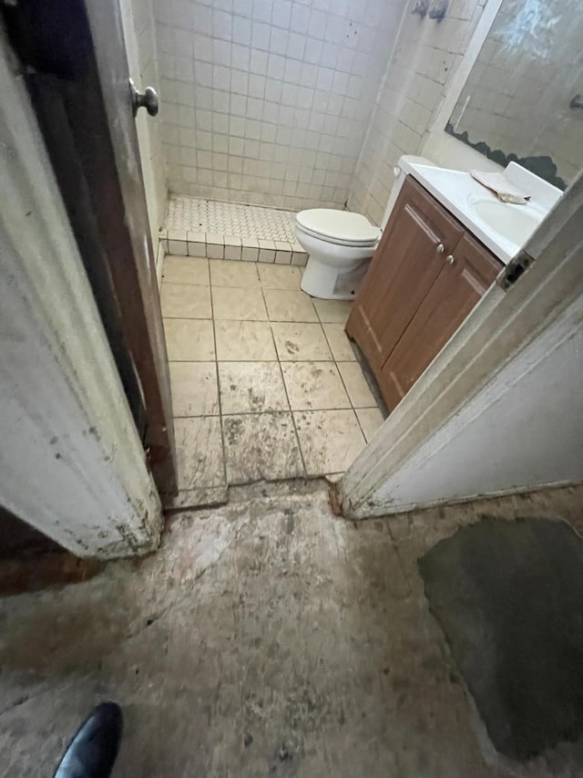 bathroom featuring tile patterned flooring, vanity, walk in shower, and toilet