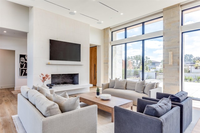 living room featuring a fireplace, light hardwood / wood-style flooring, and a high ceiling