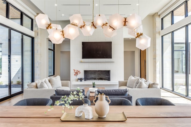 living room with hardwood / wood-style flooring, a large fireplace, expansive windows, and a towering ceiling