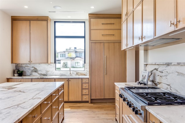 kitchen featuring sink, light stone countertops, stainless steel gas cooktop, light wood-type flooring, and light brown cabinets