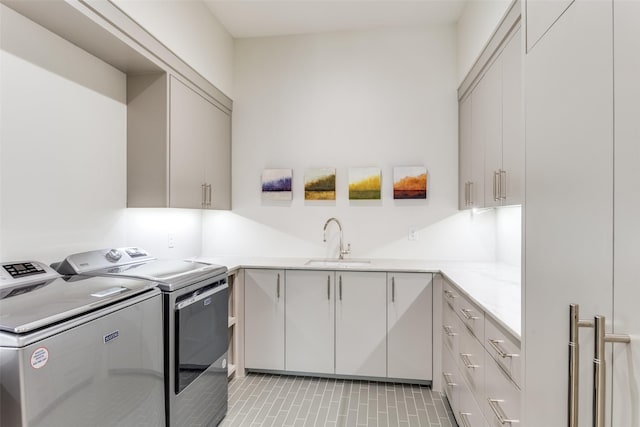 laundry area with cabinets, sink, light tile patterned floors, and washer and clothes dryer