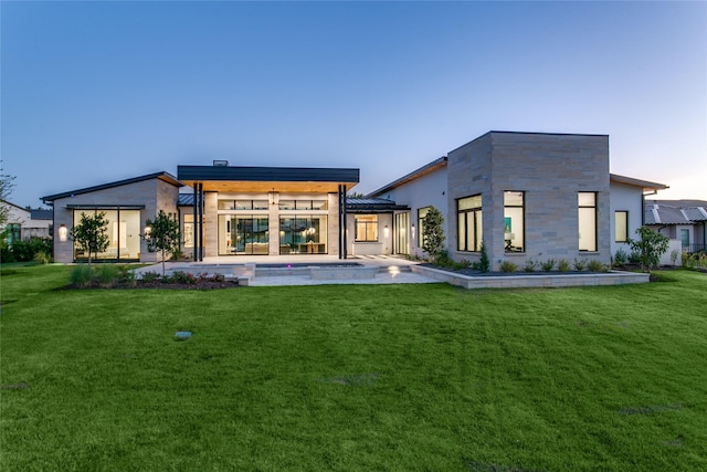 back house at dusk with a yard and a patio area