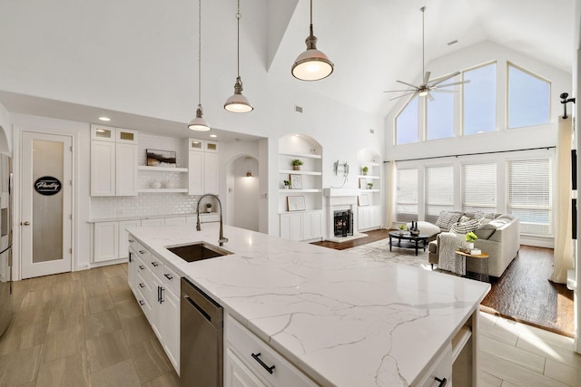 kitchen with sink, dishwasher, pendant lighting, light stone countertops, and white cabinets