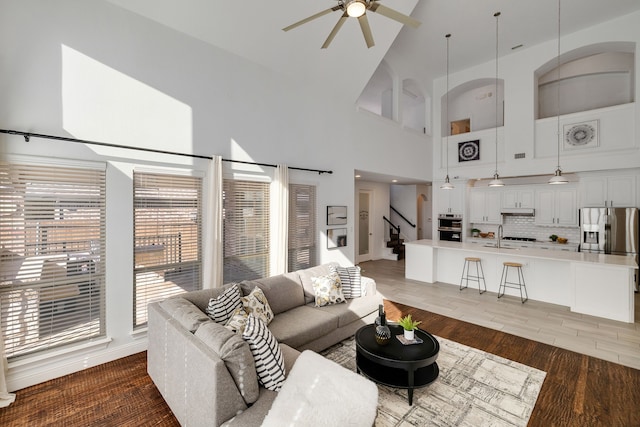 living room with dark hardwood / wood-style flooring, sink, a towering ceiling, and ceiling fan