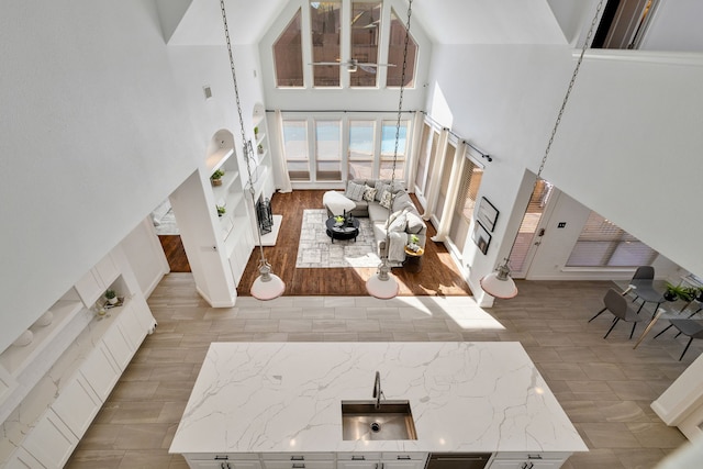 living room featuring ceiling fan, high vaulted ceiling, and sink