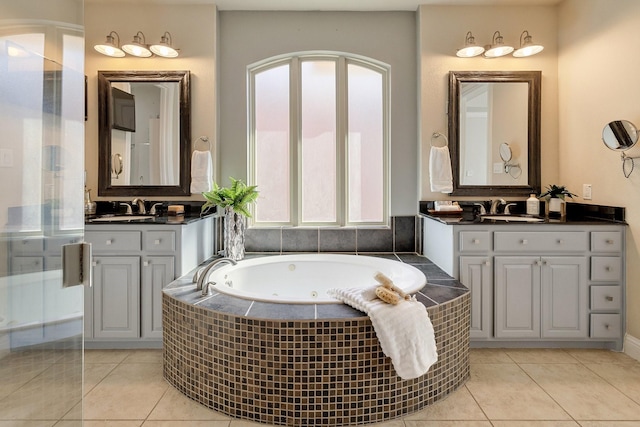 bathroom with a relaxing tiled tub, vanity, and tile patterned flooring