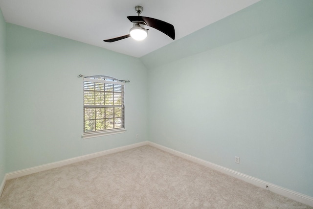 empty room featuring vaulted ceiling, light colored carpet, and ceiling fan