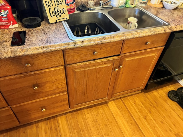 room details with sink, light stone counters, dishwashing machine, and light hardwood / wood-style floors