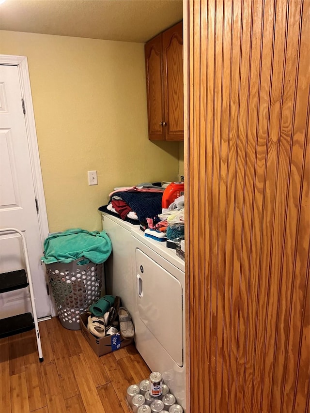 clothes washing area with cabinets, light wood-type flooring, and independent washer and dryer