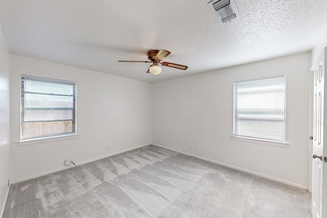 carpeted empty room featuring ceiling fan, a healthy amount of sunlight, and a textured ceiling