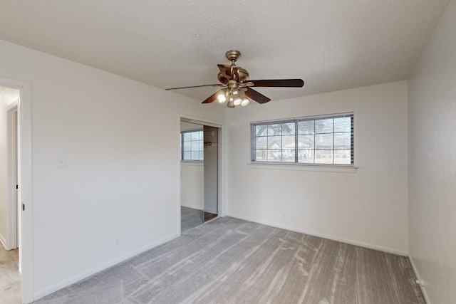 spare room featuring ceiling fan, light carpet, and a textured ceiling