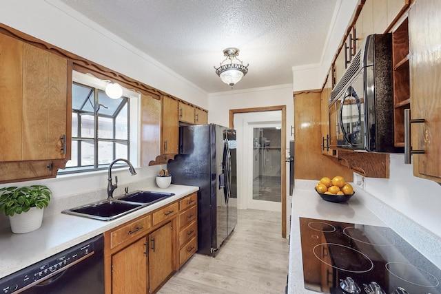 kitchen with sink, light wood-type flooring, black appliances, crown molding, and a textured ceiling