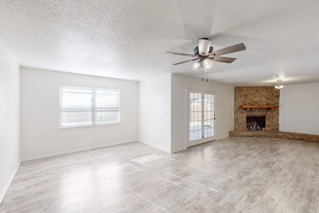 unfurnished living room featuring a stone fireplace, light hardwood / wood-style floors, and a healthy amount of sunlight