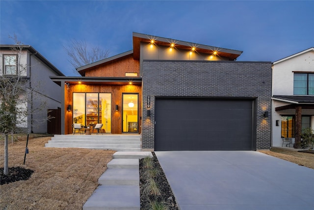 contemporary home featuring an attached garage, concrete driveway, and brick siding