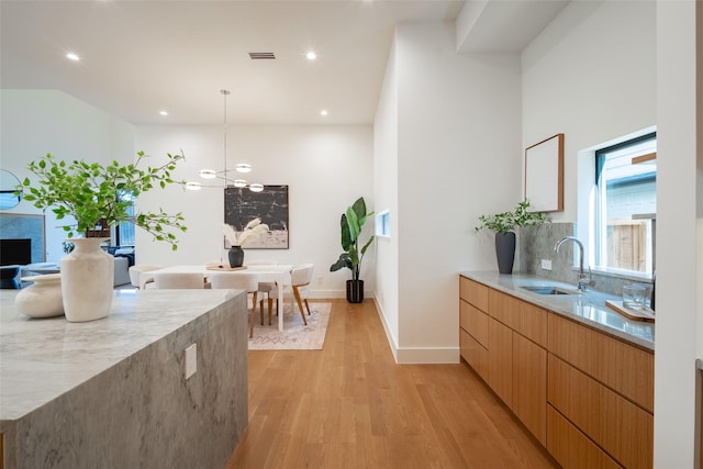 kitchen featuring a sink, visible vents, light wood-style floors, decorative backsplash, and modern cabinets