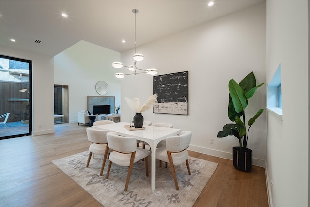 dining room with a chandelier, a premium fireplace, wood finished floors, and baseboards