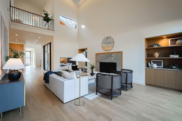 living room featuring a towering ceiling, a high end fireplace, and light hardwood / wood-style floors