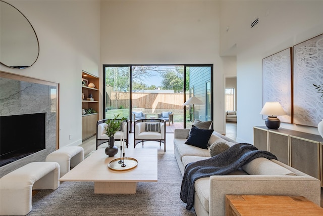 living area featuring built in features, a high end fireplace, and a towering ceiling