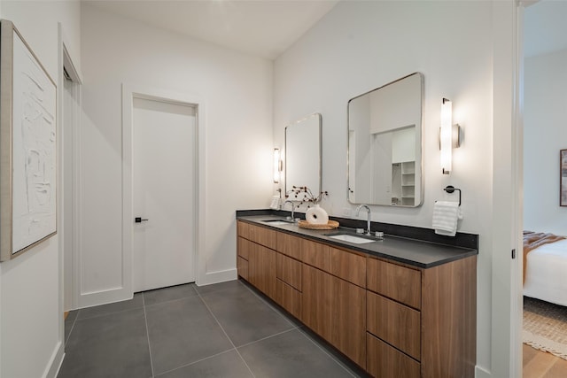 ensuite bathroom with connected bathroom, double vanity, a sink, and tile patterned floors