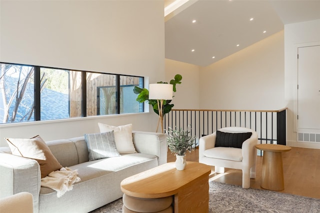 living room featuring recessed lighting, visible vents, a towering ceiling, and wood finished floors