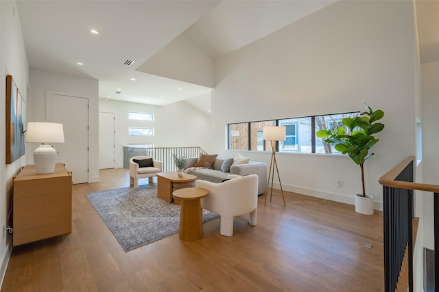 living area featuring visible vents, baseboards, wood finished floors, vaulted ceiling, and recessed lighting