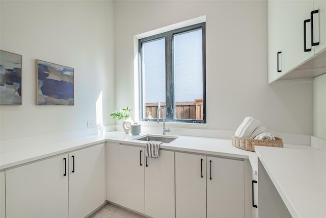 kitchen featuring white cabinets, light countertops, and a sink