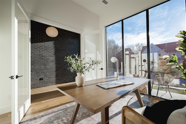 home office featuring brick wall and wood finished floors