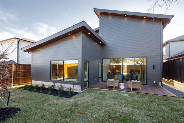 back of property with fence, a deck, and a yard