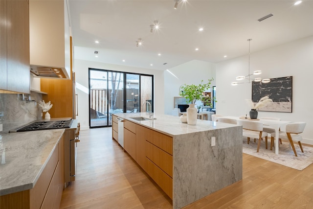 kitchen featuring visible vents, decorative backsplash, a sink, modern cabinets, and light wood-type flooring