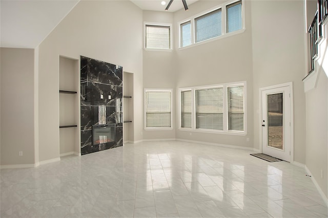 unfurnished living room featuring a towering ceiling and a high end fireplace