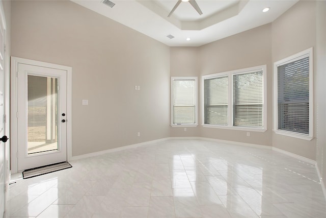 unfurnished room with a raised ceiling, ceiling fan, and a high ceiling